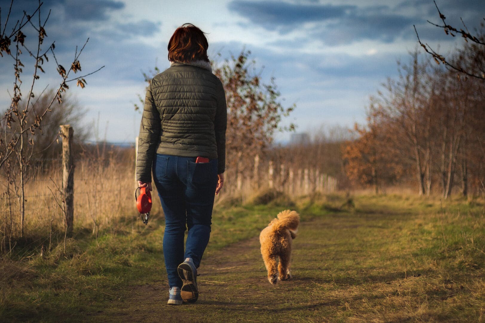 Woman walking dog on path.