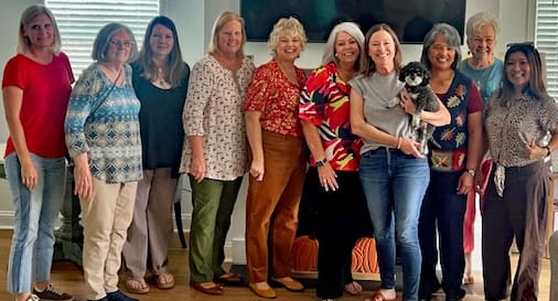 Group of women smiling with a small dog.