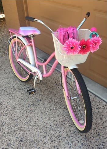 Pink bicycle with flowers in basket.