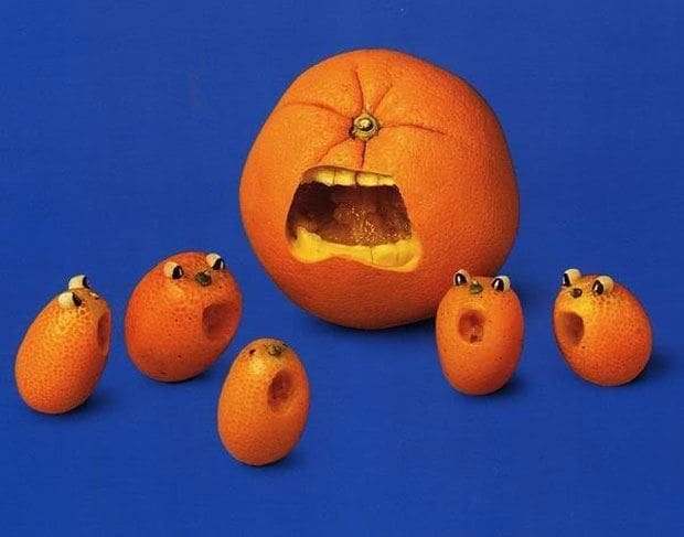 A group of oranges with eyes on them and an orange with a face in it.