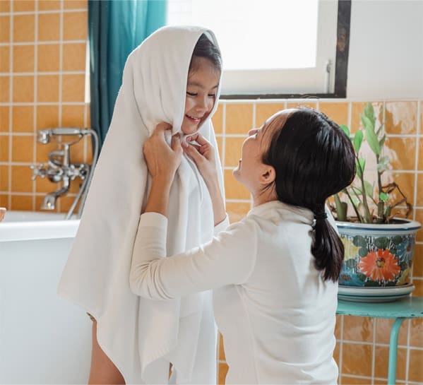 Woman drying child in white towel.