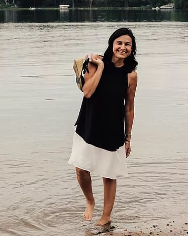 Woman in black and white dress by lake.