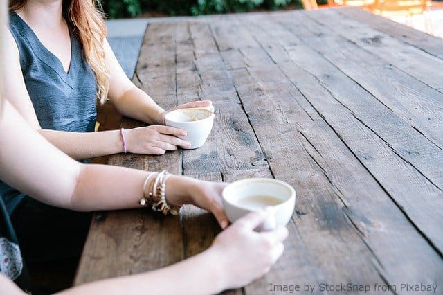 Two women sharing coffee at a table.