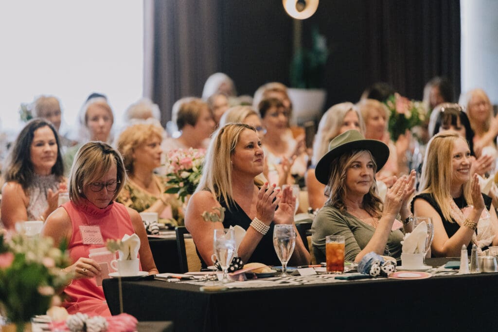 A group of women sitting at tables with food.