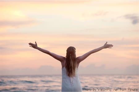 Woman embracing ocean sunset freedom.