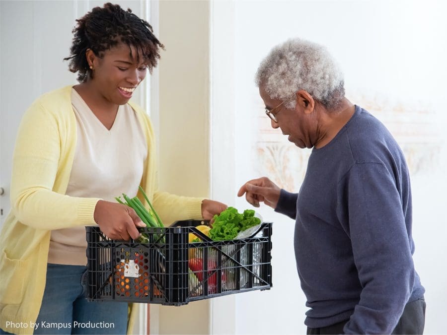 Woman giving senior man groceries.