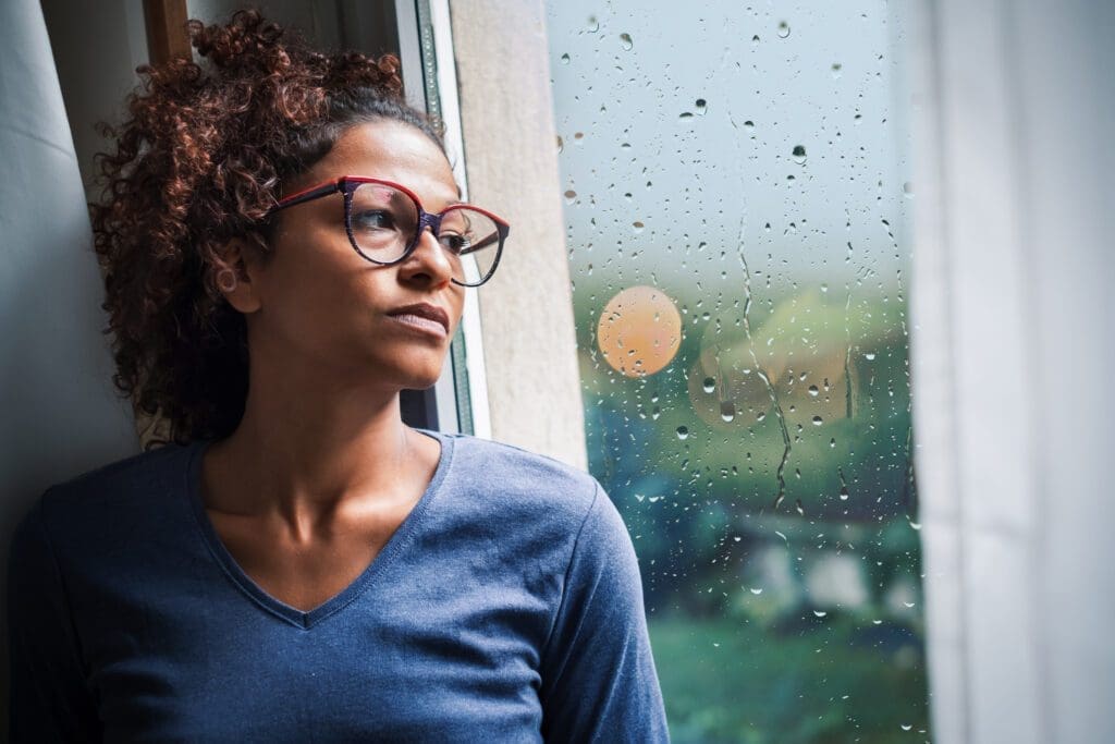 Woman looking out rainy window, pensive.