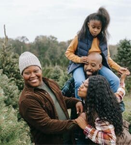 Here's an alt tag for the image: Happy family choosing a Christmas tree.