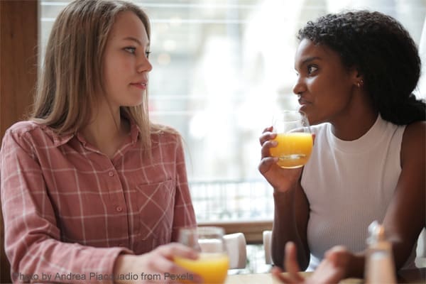 Two women talking over orange juice.