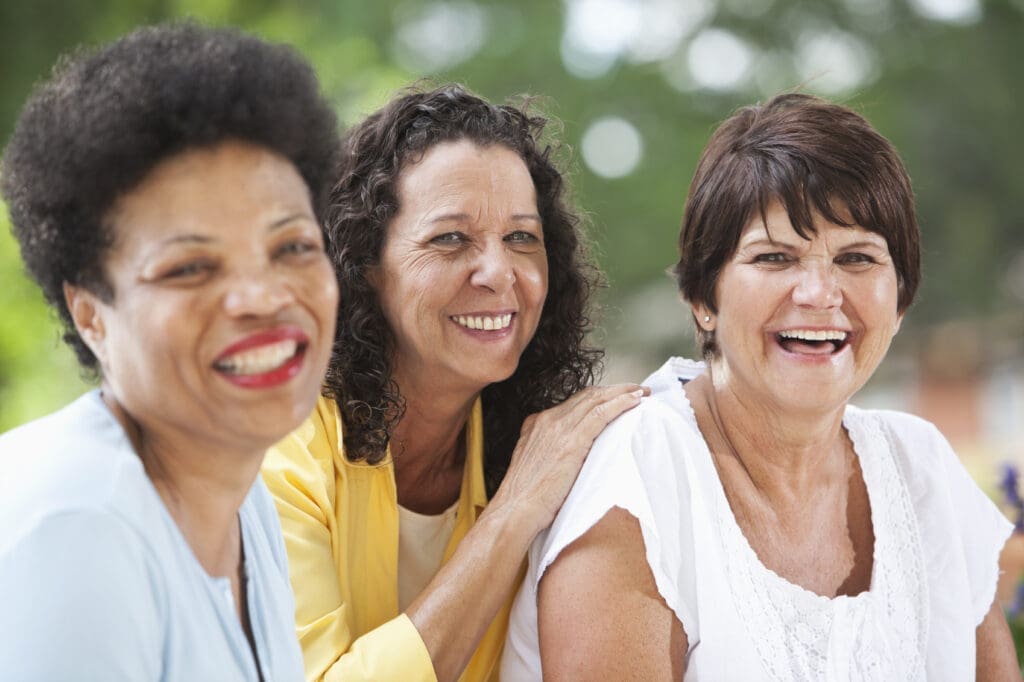 Here's an alt tag for the image: Three happy senior women friends.