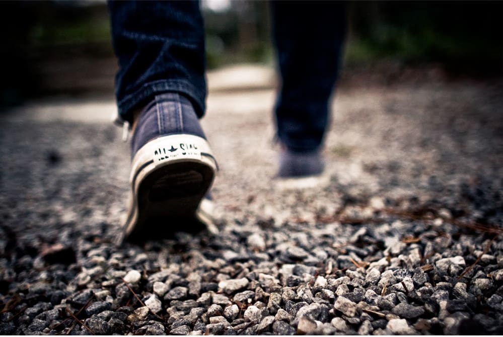 Person walking on gravel in Converse shoes.