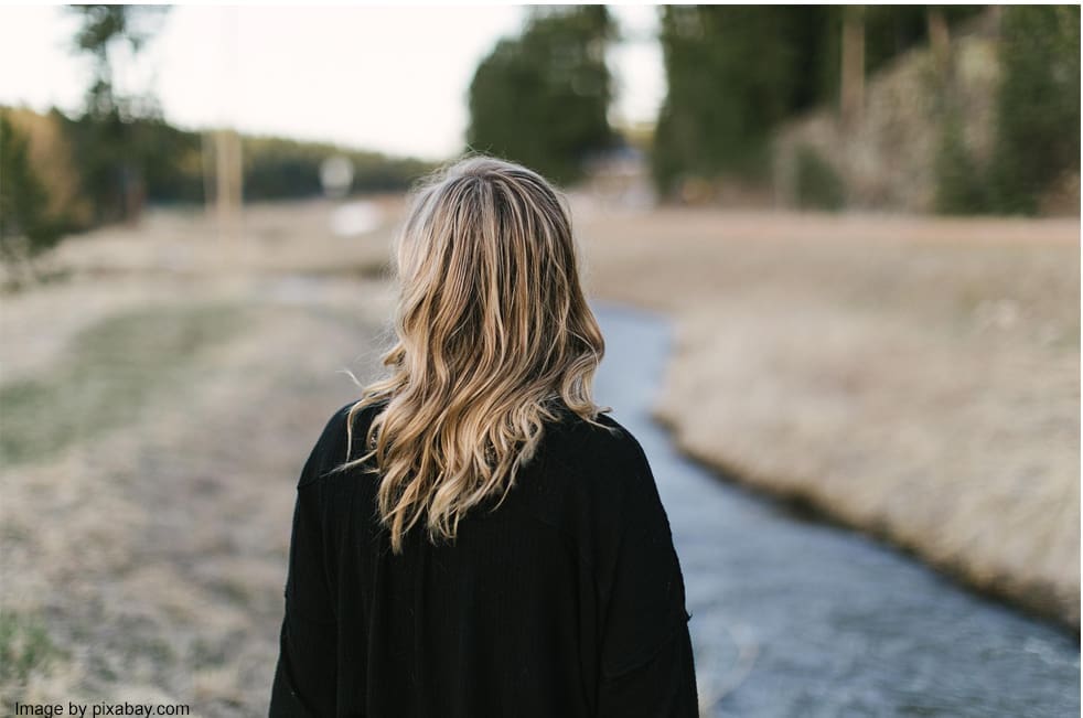 Woman standing near a small river.