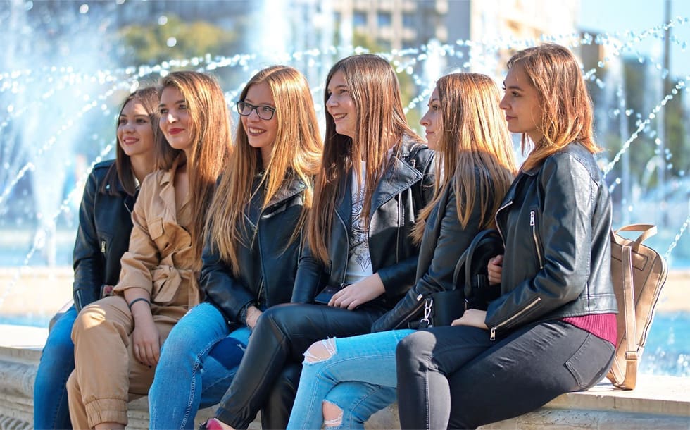 Group of women sitting by a fountain.
