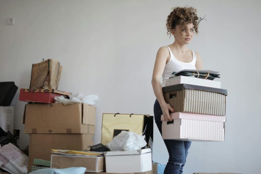 Woman carrying stacked boxes in room.