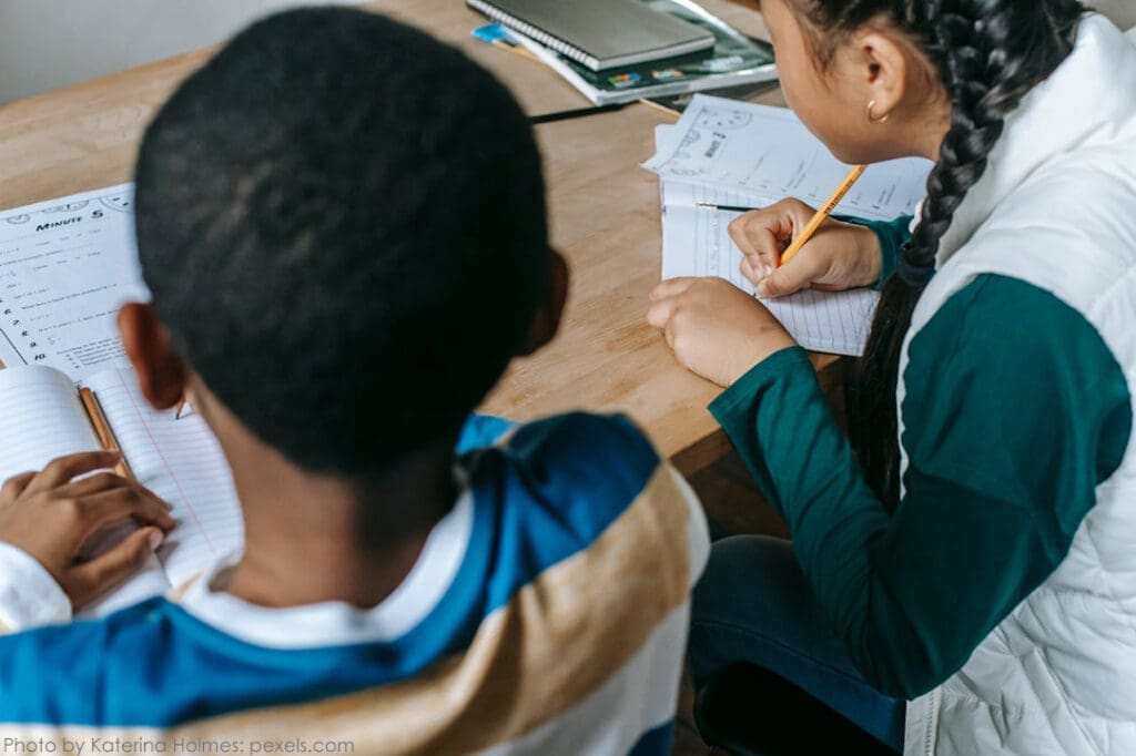 Children studying together at a wooden table.