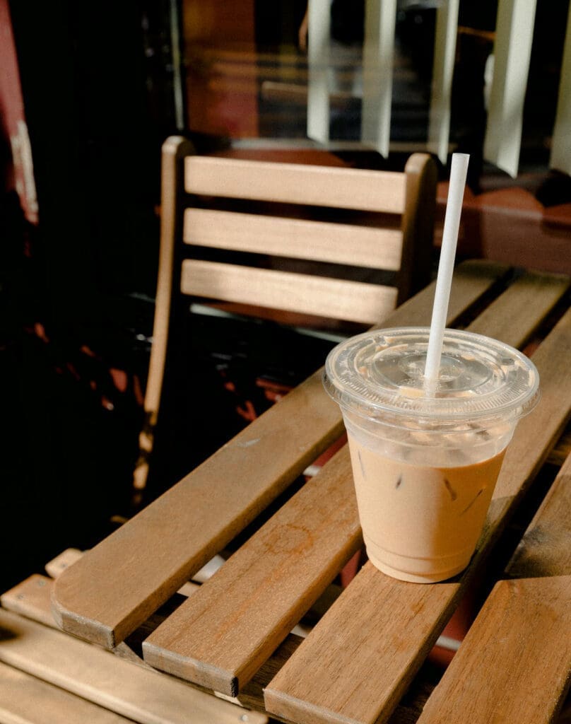 Iced coffee on wooden outdoor table.