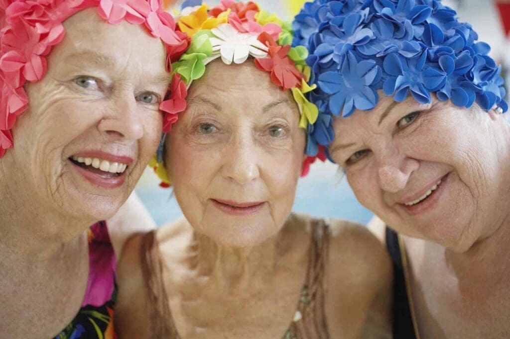 Three women wearing colorful swim caps.
